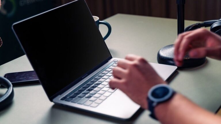 Person using a laptop beside audio equipment at a desk