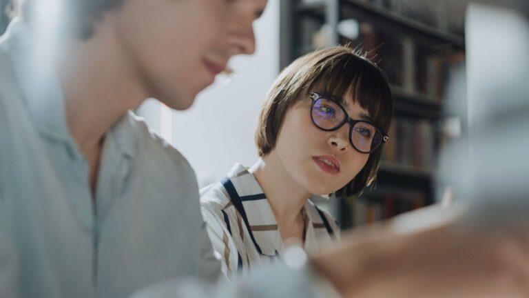 Two colleagues engage in a thoughtful discussion in a newsroom